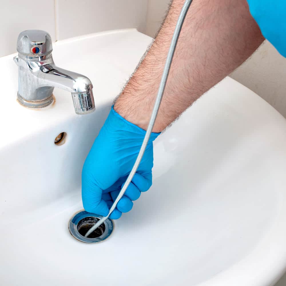 Plumber unclogging a bathroom drain